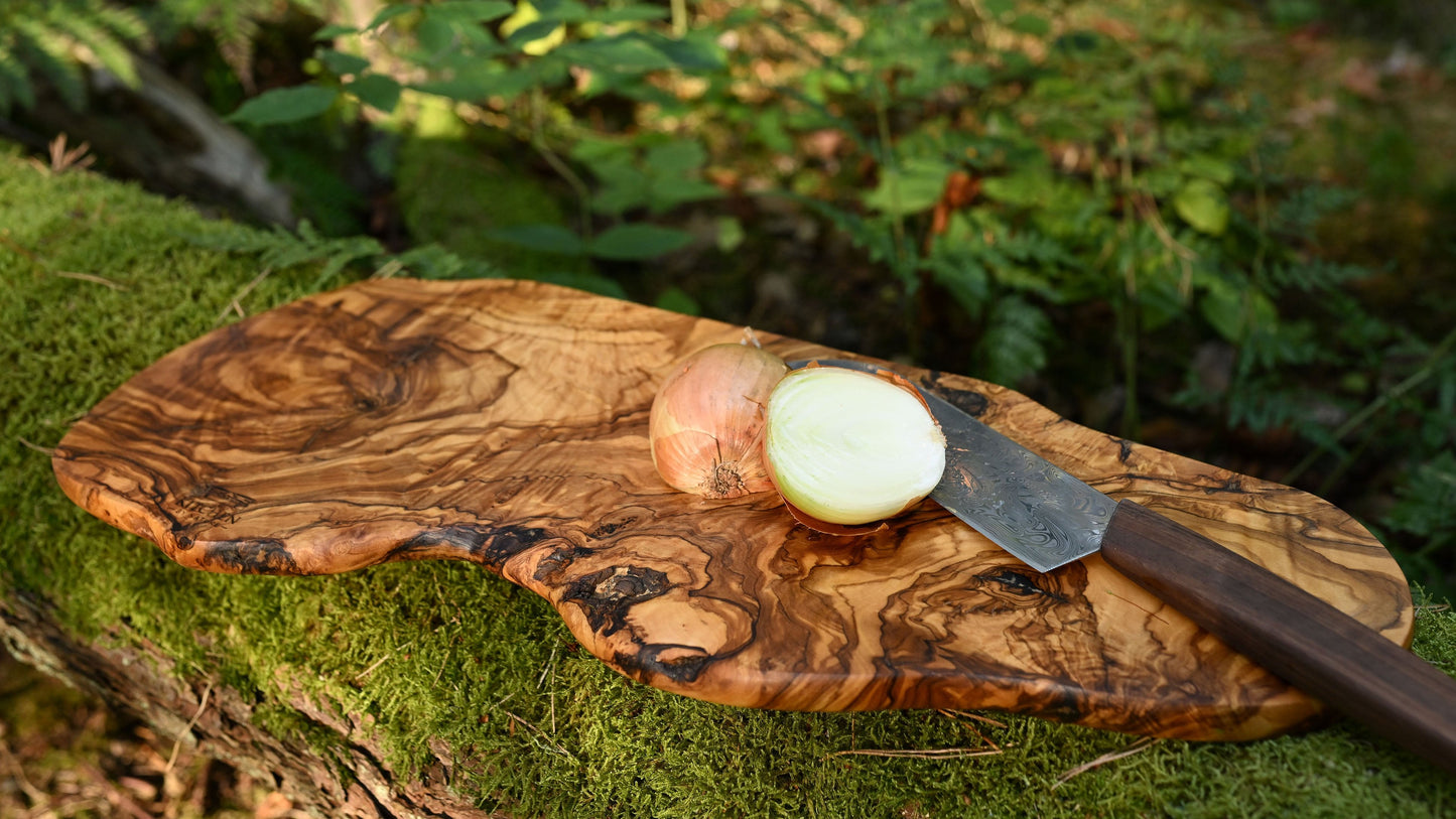 Gemasertes Holzbrett im Freien mit geschnittener Zwiebel und Messer